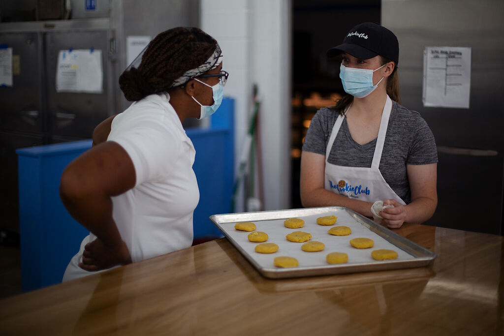 Kiarah Harris and Belle Graves talk over a sheet of unbaked cookies